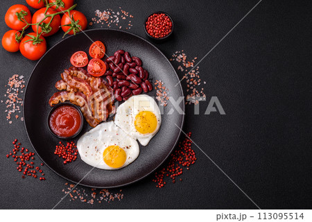 English breakfast with fried eggs, bacon, beans, tomatoes, spices and herbs 113095514
