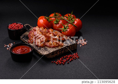 Delicious fresh fried bacon with salt and spices on a dark background Delicious fresh fried bacon with salt and spices on a dark background 113095628