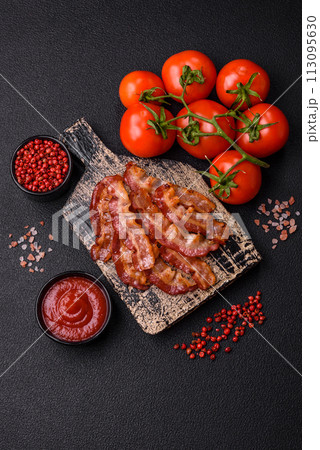 Delicious fresh fried bacon with salt and spices on a dark background 113095630