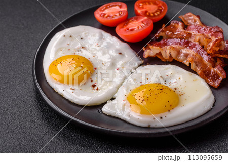 English breakfast with fried eggs, bacon, beans, tomatoes, spices and herbs 113095659