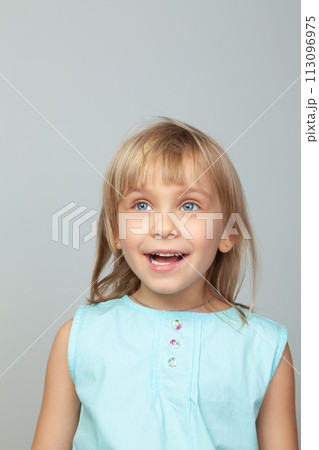 Joyful little girl smiling against a grey background 113096975