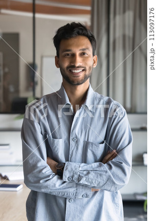 Cheerful handsome Indian businessman standing in office with hands folded 113097176