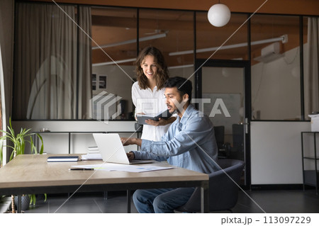 Two positive diverse business colleagues working on project at laptop Two positive diverse business colleagues working on project at laptop 113097229