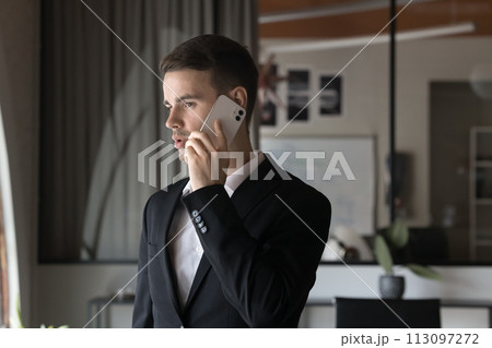 Focused busy young executive man talking on cellphone in office Focused busy young executive man talking on cellphone in office 113097272