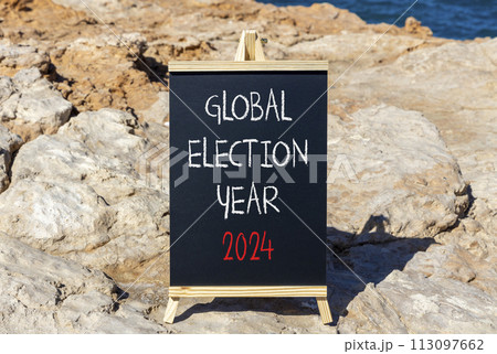Global election year 2024 symbol. Concept words Global election year 2024 on beautiful black blackboard. Beautiful stone blue sea sky background. Business Global election year 2024 concept. Copy space 113097662
