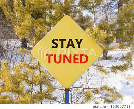 Stay tuned symbol. Concept words Stay tuned on beautiful yellow road sign. Beautiful forest snow blue sky background. Business, support, motivation, psychological and stay tuned concept. Copy space. 113097711