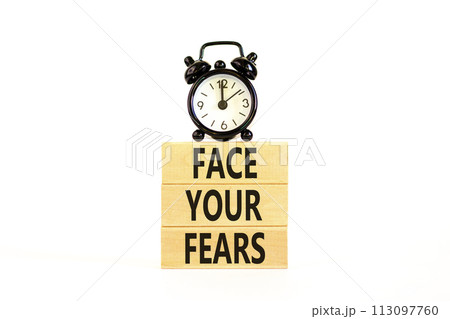 Face your fears and support symbol. Concept words Face your fears on wooden blocks. Black alarm clock. Beautiful white table white background. Business and Face your fears quote concept. Copy space. 113097760