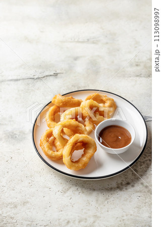 Crisp fried golden squid rings with lemon and sauce on a plate, isolated, text space Crisp fried golden squid rings with lemon and sauce on a plate, isolated, text space 113098997