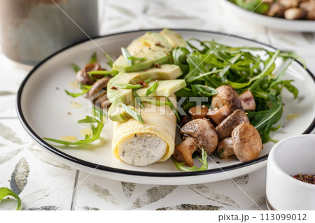 French rolled omelette stuffed with cream cheese with avocado, aragula and mushrooms for breakfast on white plate close up printed tile French rolled omelette stuffed with cream cheese with avocado, aragula and mushrooms for breakfast on white plate close up printed tile 113099012