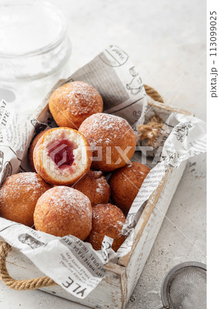 Cottage cheese donuts balls stuffed with jam with powdered sugar in wooden box. Healthy curd dessert. Selective focus Cottage cheese donuts balls stuffed with jam with powdered sugar in wooden box. Healthy curd dessert. Selective focus 113099025