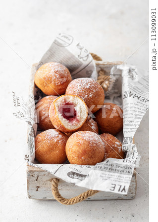 Cottage cheese donuts balls stuffed with jam with powdered sugar in wooden box. Healthy curd dessert. Selective focus Cottage cheese donuts balls stuffed with jam with powdered sugar in wooden box. Healthy curd dessert. Selective focus 113099031