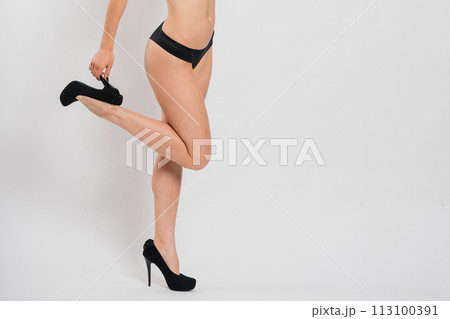 Cute brunette female model posing, wearing black and red underwear in white studio 113100391