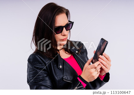 A frustrated young woman with a broken phone in her hands. White isolated background. Broken Gadget A frustrated young woman with a broken phone in her hands. White isolated background. Broken Gadget 113100647