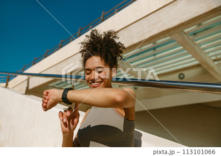 Smiling fit woman looking at smartwatch and counting calories burned. Healthy life concept 113101066