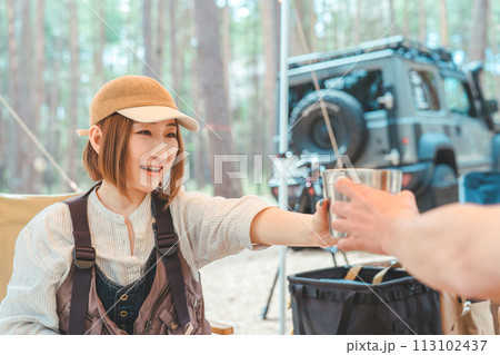 キャンプ場でステンレスカップでビールを飲む夫婦・カップルキャンパー キャンプ場でステンレスカップでビールを飲む夫婦・カップルキャンパー 113102437