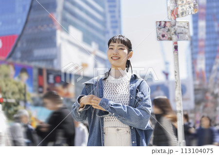 都会の街角に立つカメラ目線で笑顔の若い女性 ポートレート 都会の街角に立つカメラ目線で笑顔の若い女性 ポートレート 113104075