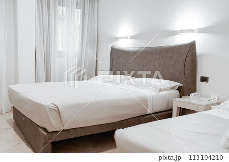 Minimal double bed with white mattress in luxury hotel bedroom. Comfortable bed 113104210