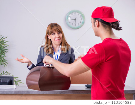 Young male courier delivering cake to hotel's reception 113104588