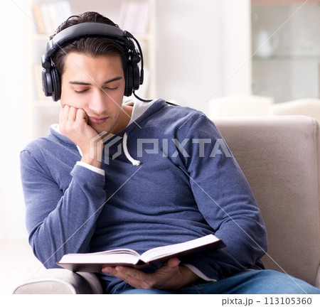 Young man reading book and listening to audio book Young man reading book and listening to audio book 113105360