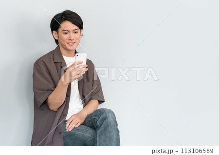 スマホを使う若いアジア人男性(ストレートネック・巻き肩・猫背・ドライアイ・スマホ老眼・眼精疲労) スマホを使う若いアジア人男性(ストレートネック・巻き肩・猫背・ドライアイ・スマホ老眼・眼精疲労) 113106589