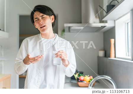 キッチンで内服薬・サプリ・医薬品を飲む病気の男性・投薬 113106713