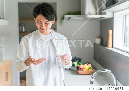 キッチンで内服薬・サプリ・医薬品を飲む病気の男性・投薬 113106714