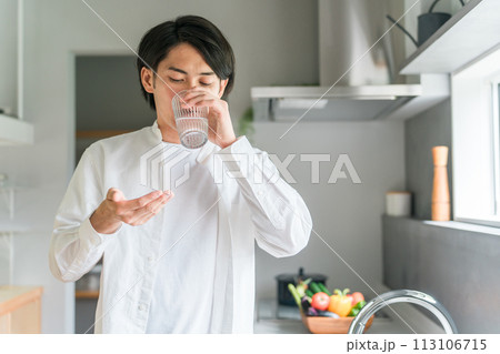 キッチンで内服薬・サプリ・医薬品を飲む病気の男性・投薬 113106715