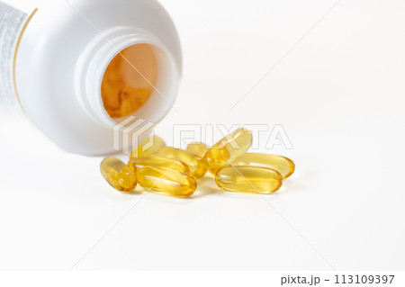 Yellow fish oil capsules in a jelly shell near the white jar Yellow fish oil capsules in a jelly shell near the white jar 113109397