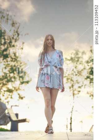 Young woman walking along park alley 113109452