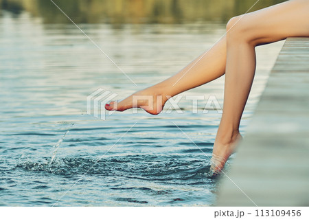 Unrecognizable woman splashing her feet in water 113109456