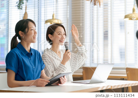 マイクを持って質問をする女性 113111434