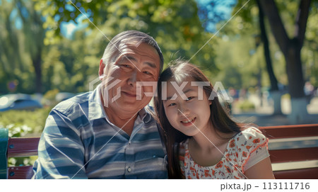 Adult father with younger daughter on park bench, portrait of happy central asian family, caring concept and Father's Day poster 113111716