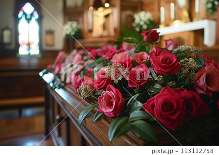 Close up view of a brown wooden coffin decorated with red roses in a church 113112758