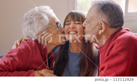 Grandparents kissing their granddaughter while she visits them 113112929