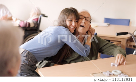 Granddaughter embracing her senior grandfather in a geriatric 113112931