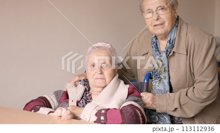 Senior women looking at camera together in a nursing home Senior women looking at camera together in a nursing home 113112936