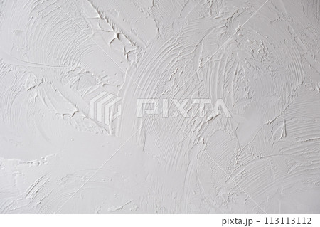 Applying decorative putty. White abstract texture of surface covered with putty. textured background of filler paste applied with putty knife in irregular dashes and strokes. Rough surface plaster 113113112