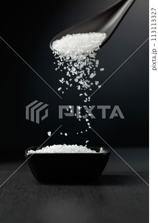 Sea salt is poured into a black bowl. Sea salt is poured into a black bowl. 113113327