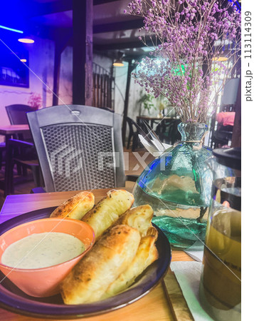 Breakfast in a cafe with a cup of coffee and pastries. Creamy sauce in a bowl and fried bread on the table Breakfast in a cafe with a cup of coffee and pastries. Creamy sauce in a bowl and fried bread on the table 113114309