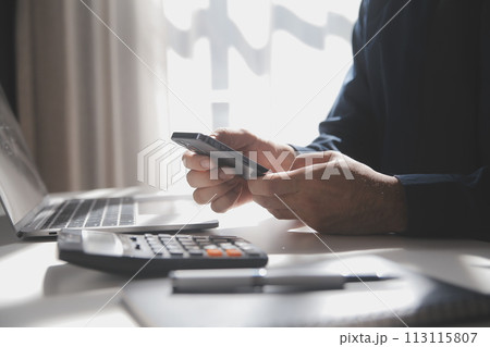 Side view shot of a man's hands using smart phone in interior, rear view of business man hands busy using cell phone at office desk, young male student typing on phone sitting at wooden table, flare 113115807