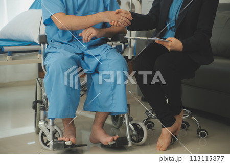 Midsection of female nurse checking blood pressure of woman sitting on wheelchair in clinic 113115877