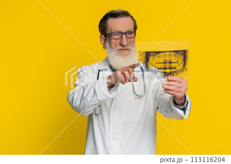 Senior doctor orthodontist man examines a panoramic x-ray picture of the jaw teeth stomatology 113116204