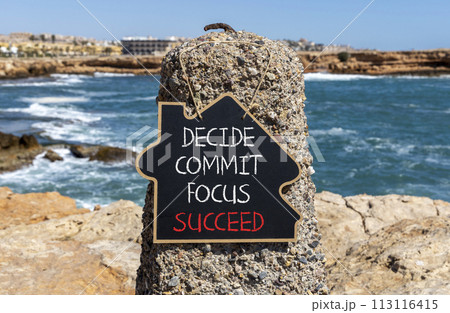 Decide commit focus succeed symbol. Concept word Decide Commit Focus Succeed on beautiful blackboard. Beautiful red stone blue sea background. Business decide commit focus succeed concept. Copy space. 113116415
