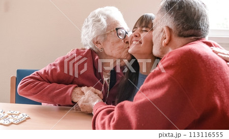 Happy grandparents hugging and kissing granddaughter in nursing home 113116555