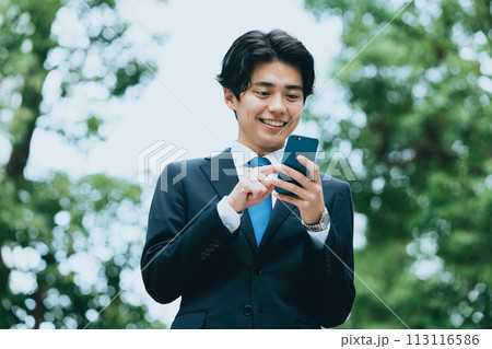 屋外でスマホを見るビジネスマン 屋外でスマホを見るビジネスマン 113116586