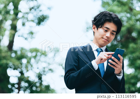 屋外でスマホを見るビジネスマン 屋外でスマホを見るビジネスマン 113116595