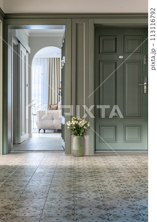 House hallway with a green door and floral vase fixture on wood flooring 113116792
