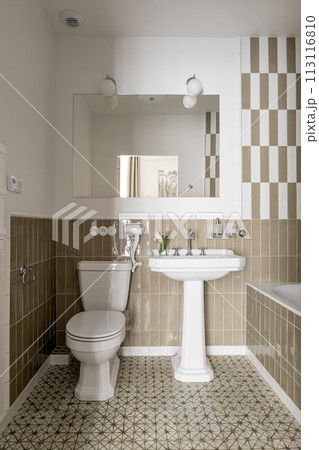 A bathroom with a toilet, sink, mirror, and bathtub A bathroom with a toilet, sink, mirror, and bathtub 113116810
