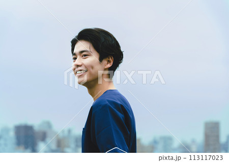 ビルを背景に微笑む若い男性医療従事者 113117023