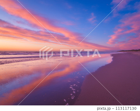 Seascape during sunrise. Bright clouds on the sky. Lines of sand on the seashore. 113117130